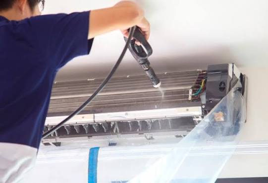 Technicien nettoyant climatisation au Karcher haute pression